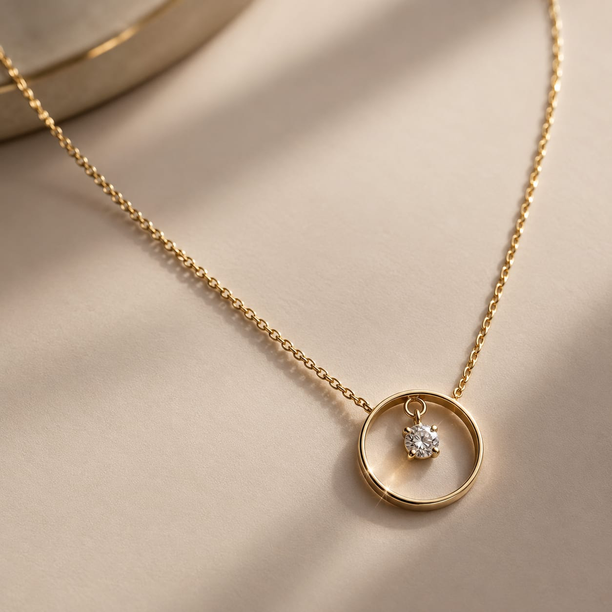 Pendentif en or jaune : un anneau suspendu à une chaîne fine, avec un diamant serti au centre.